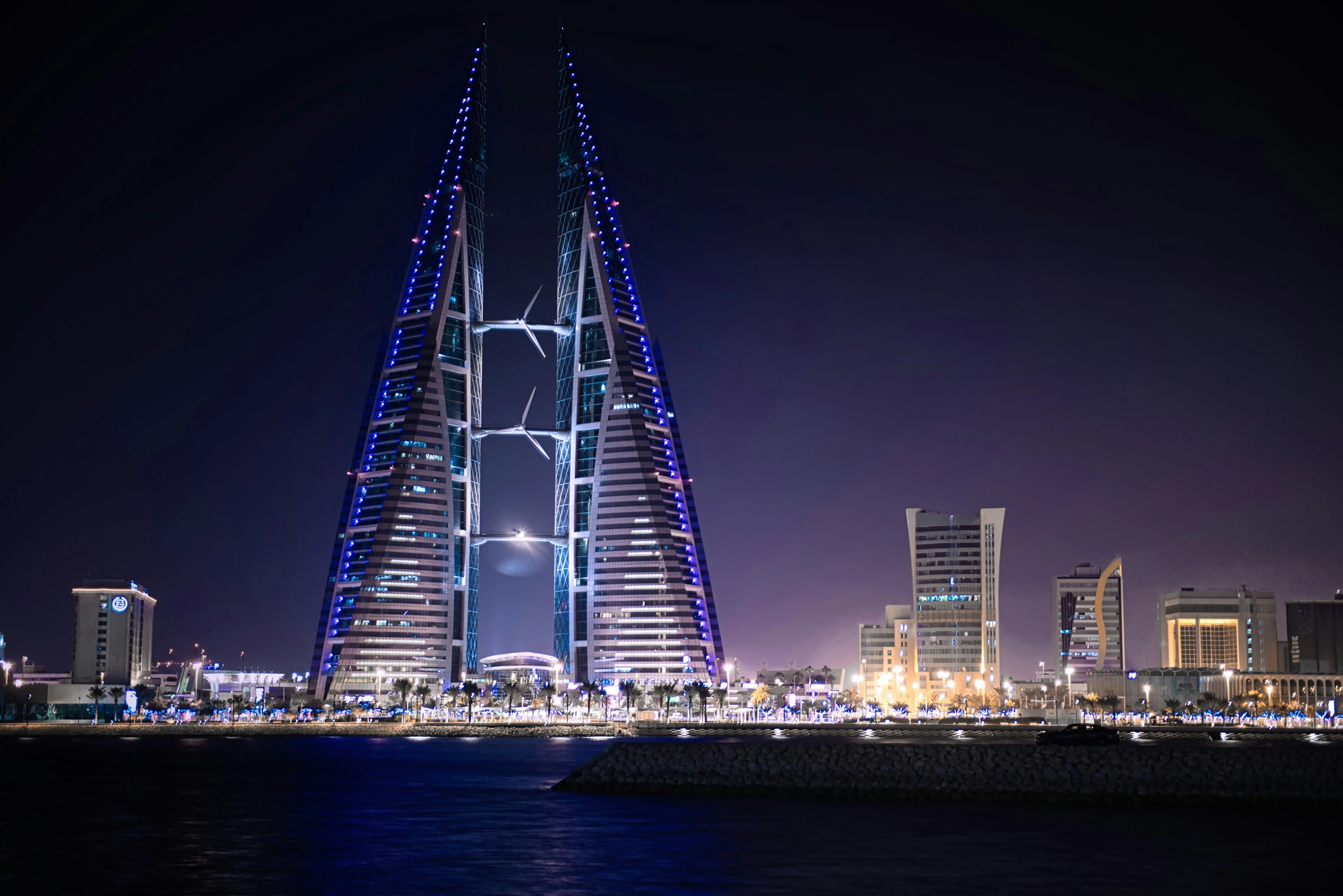 Les tours jumelles du Bahrain World Trade Center et leurs éoliennes illuminées la nuit, à Manama