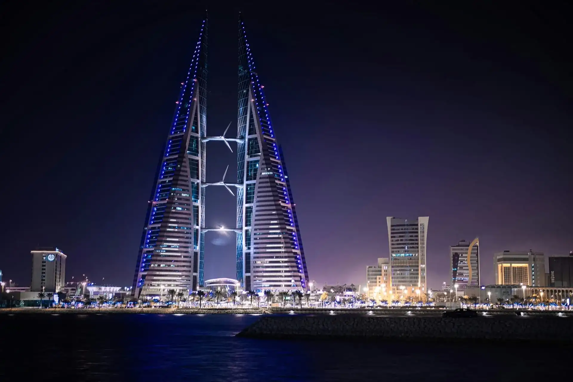Les tours jumelles du Bahrain World Trade Center et leurs éoliennes illuminées la nuit, à Manama