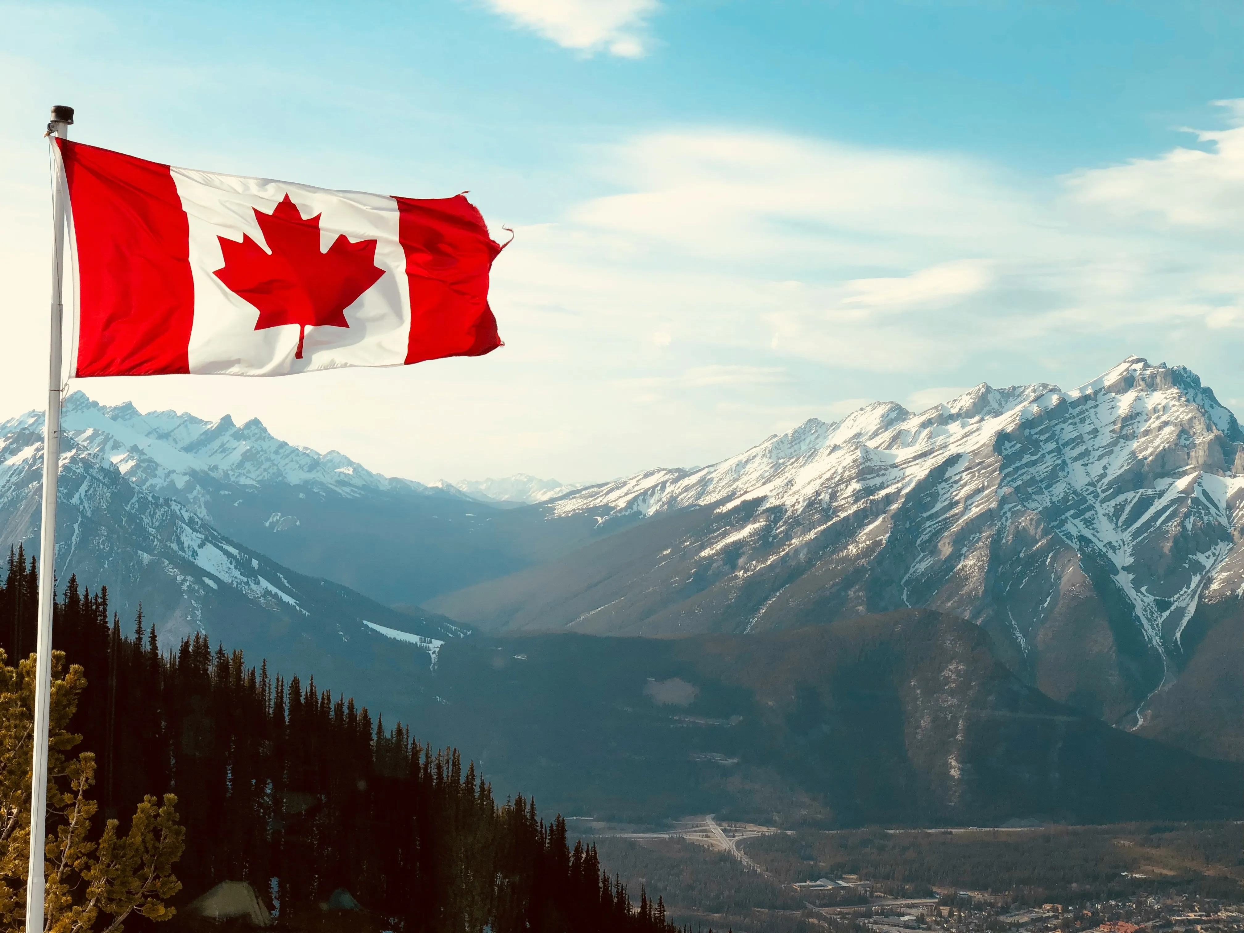 Drapeau canadien flottant devant les sommets enneigés des Rocheuses, à Banff