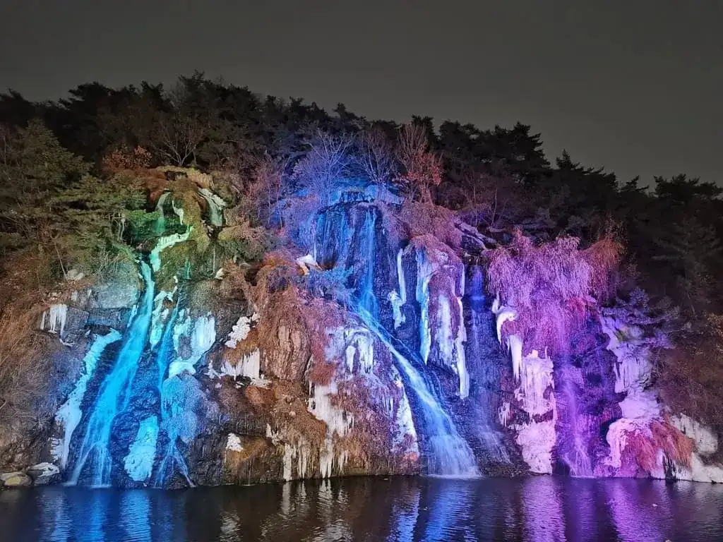 La cascade artificielle de Hongjecheon illuminée de bleu et de violet à la nuit tombée