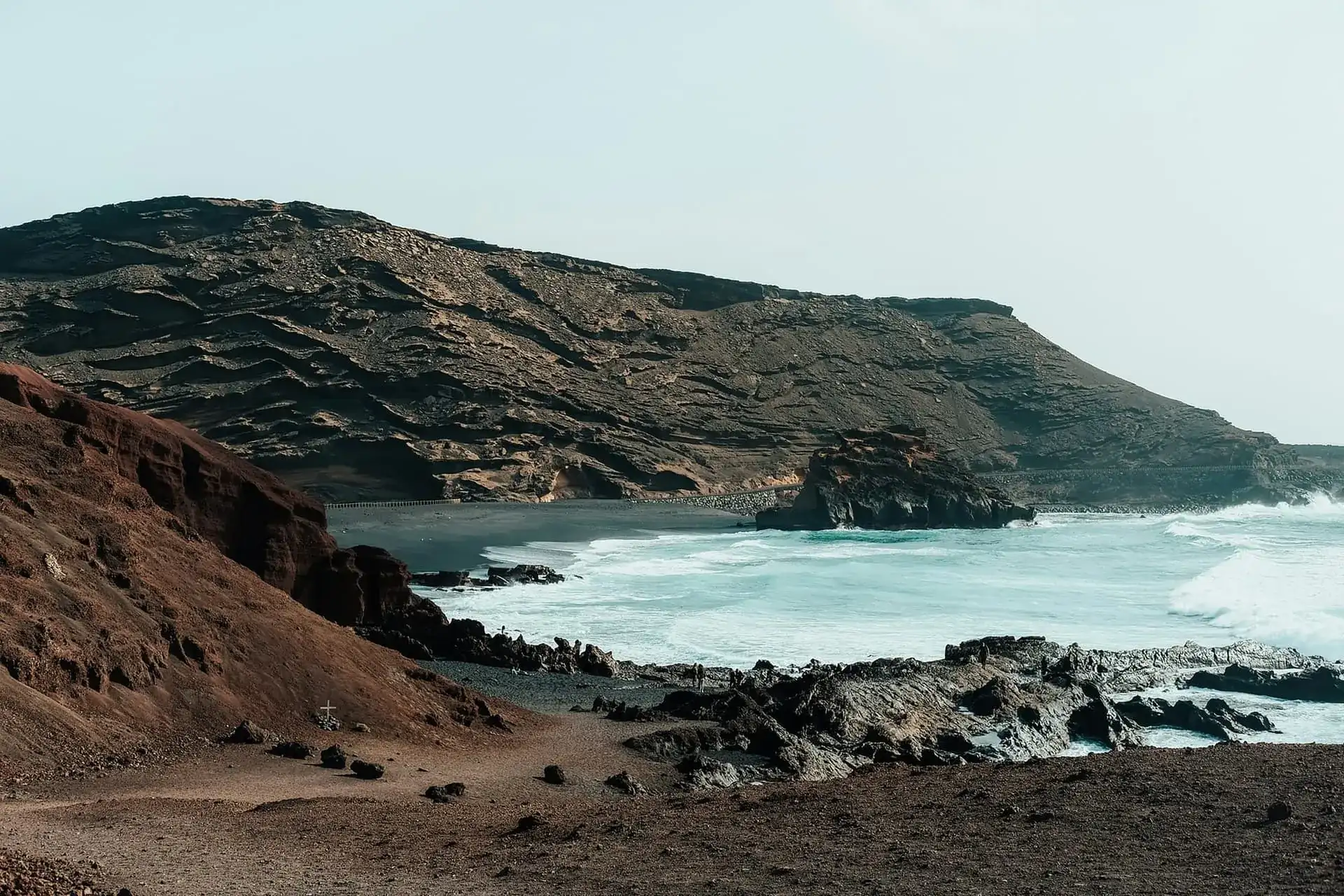 Côte rocheuse sombre et plage de sable noir battues par les vagues de l'Atlantique