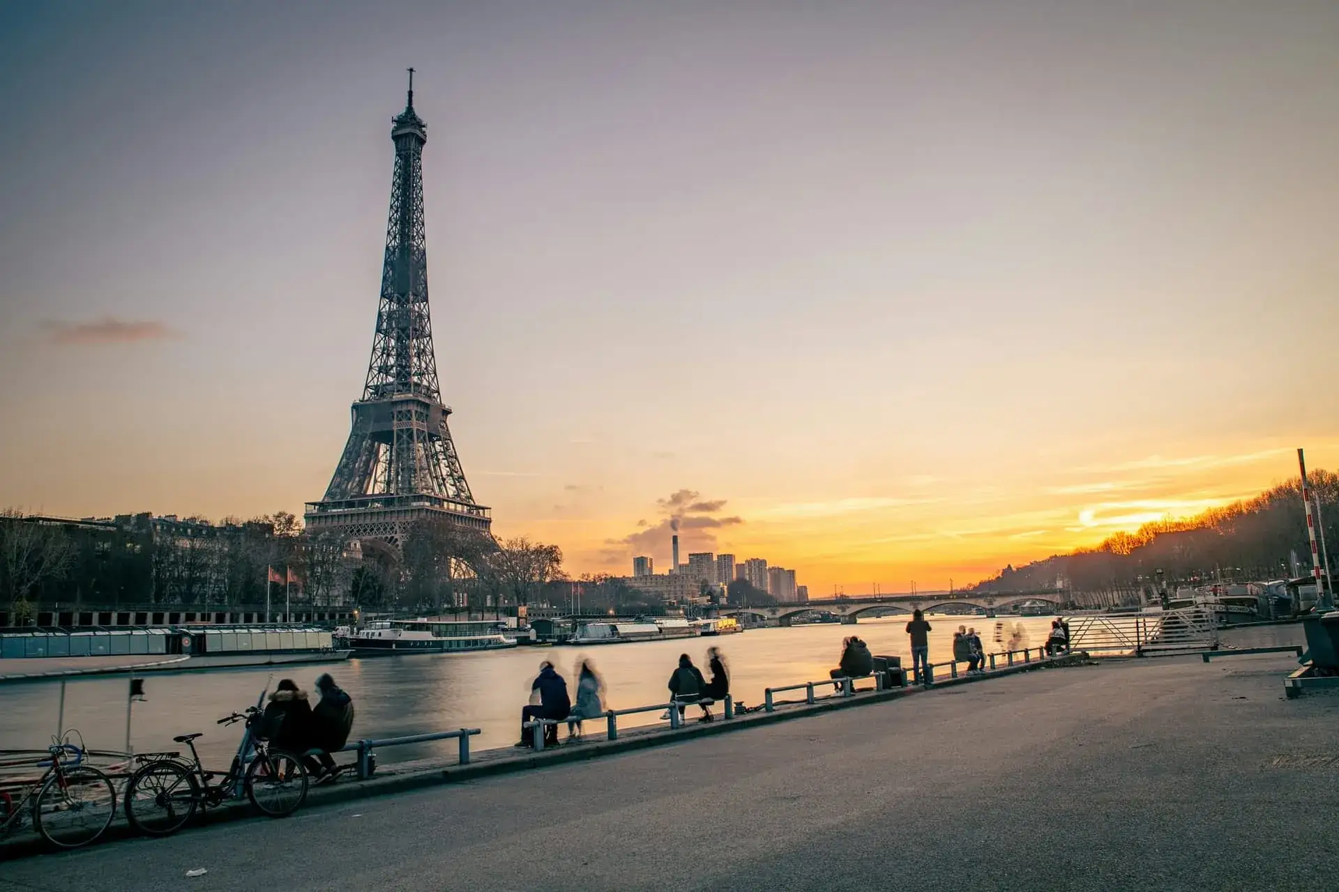 La tour Eiffel au coucher du soleil depuis les quais de Seine, promeneurs assis face au fleuve