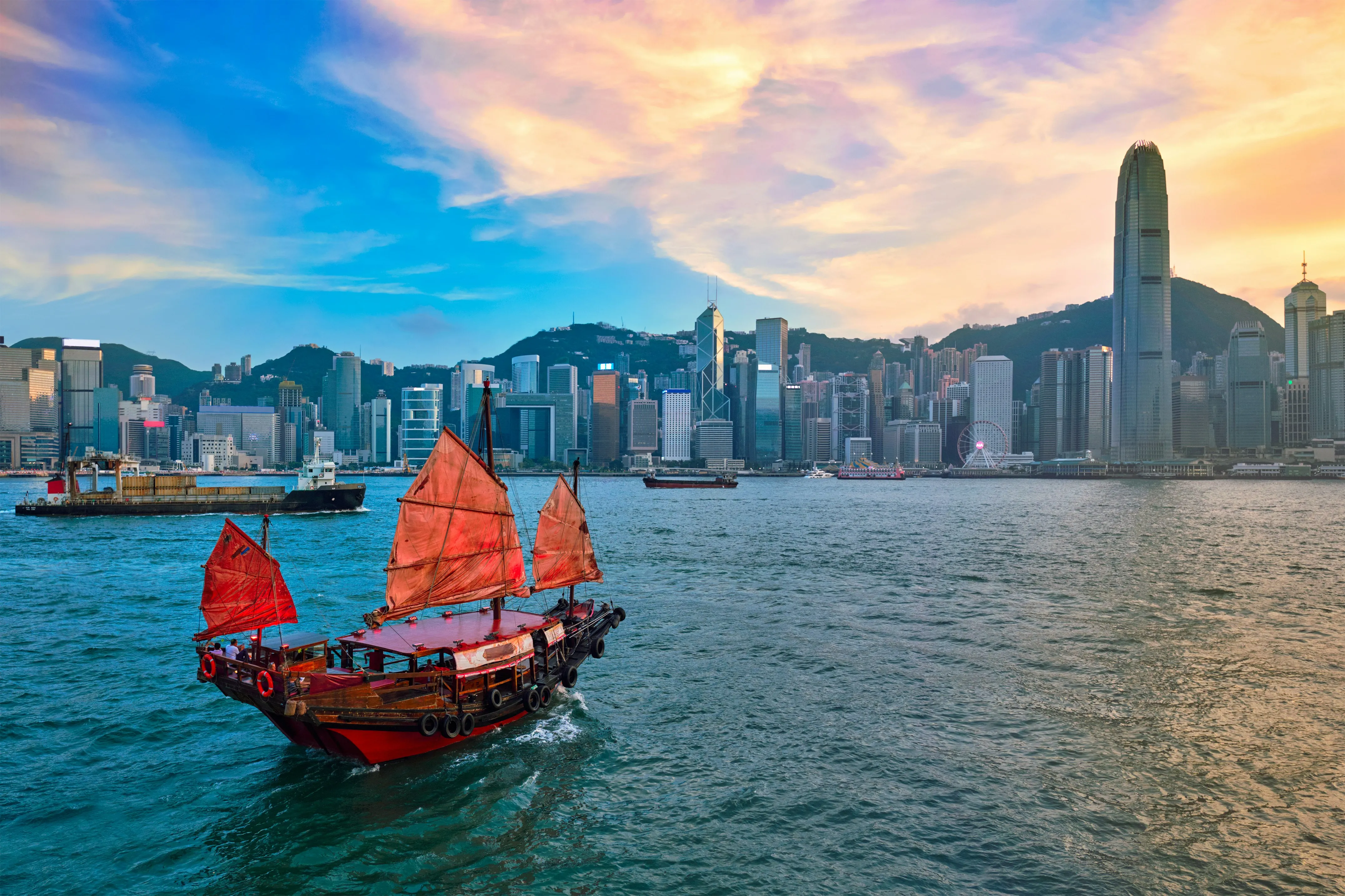 Une jonque aux voiles rouges traversant le port Victoria devant la skyline de Hong Kong