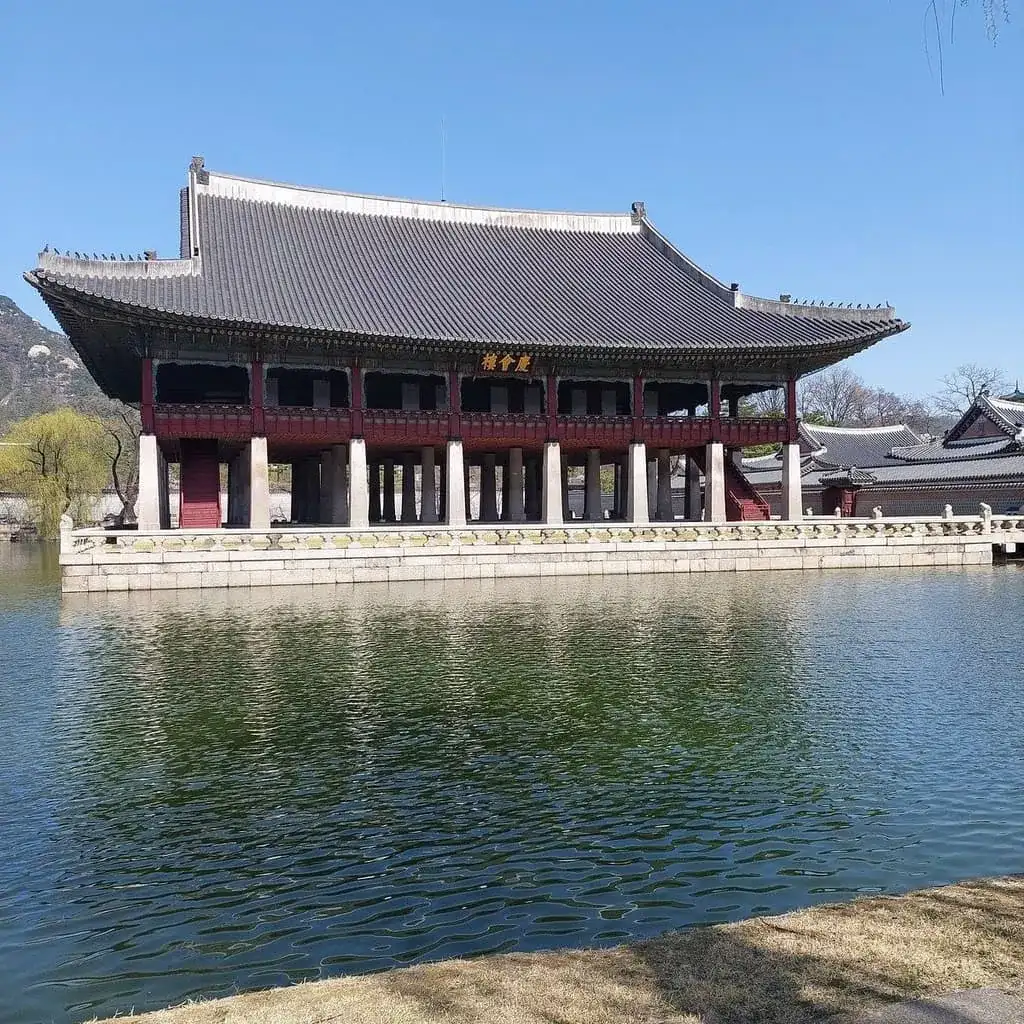 Un pavillon de bois du palais Changgyeonggung au bord de son étang, sous un ciel bleu