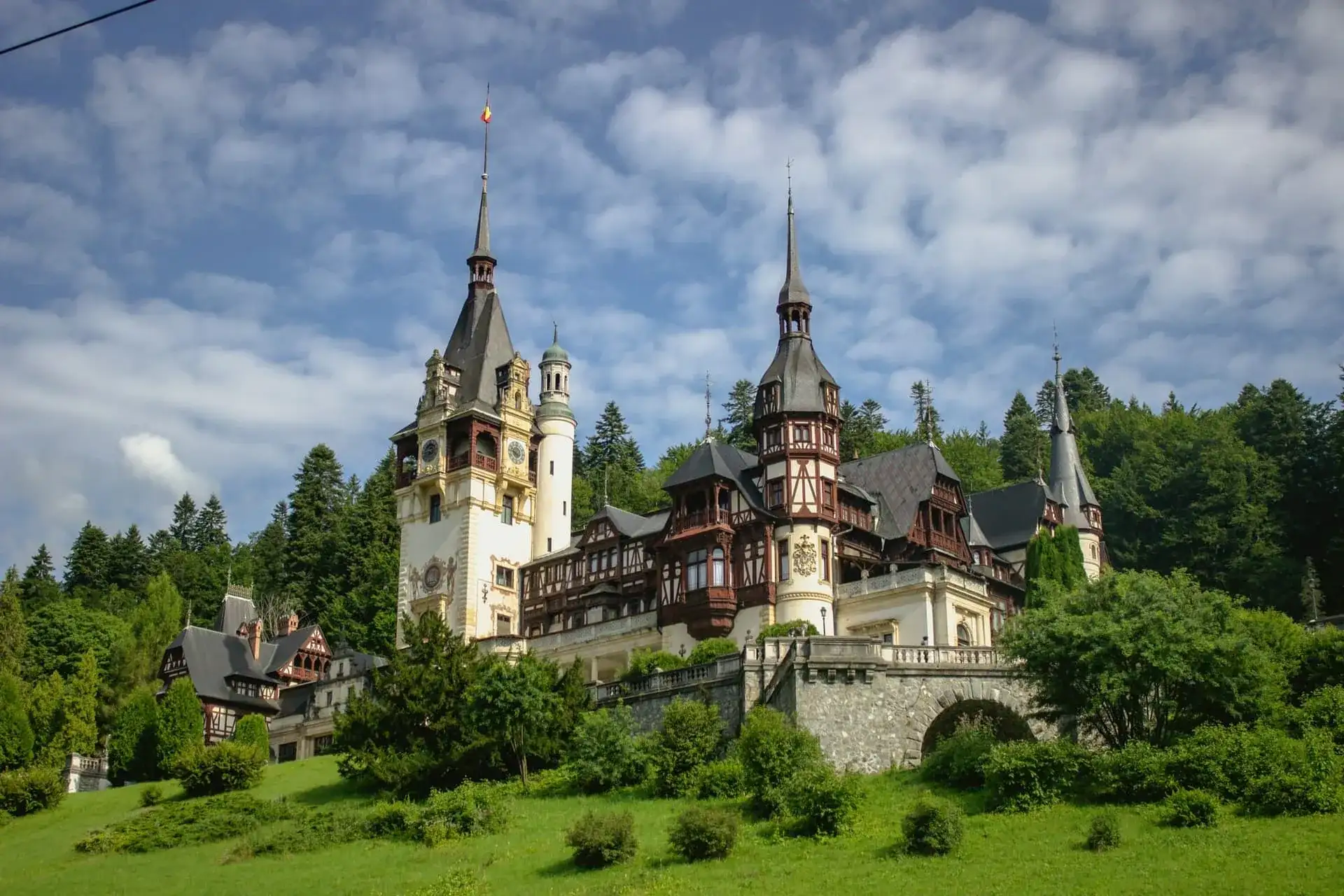 Le château de Peleș et ses tourelles à colombages sur fond de forêt des Carpates, à Sinaia