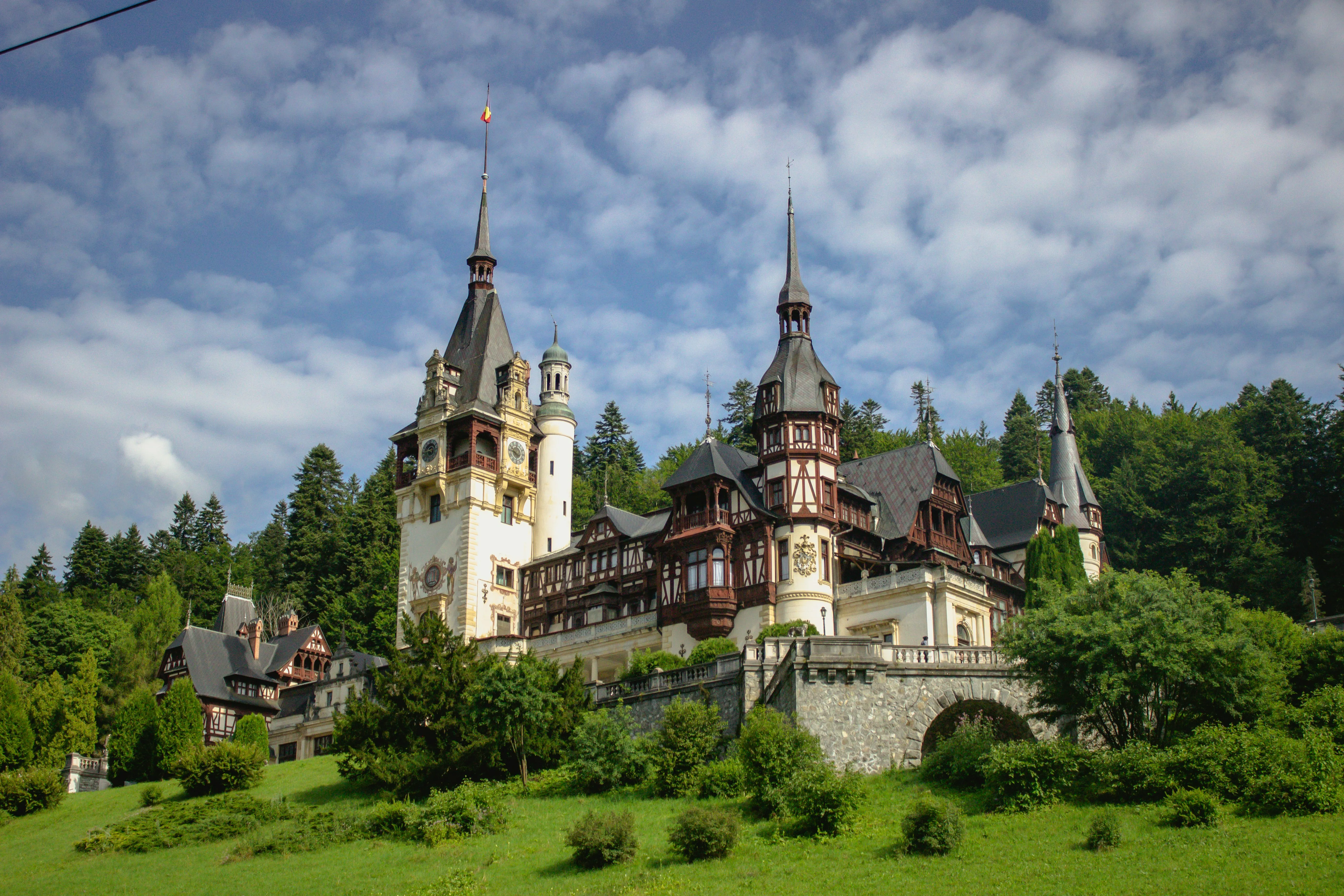 Le château de Peleș et ses tourelles à colombages sur fond de forêt des Carpates, à Sinaia