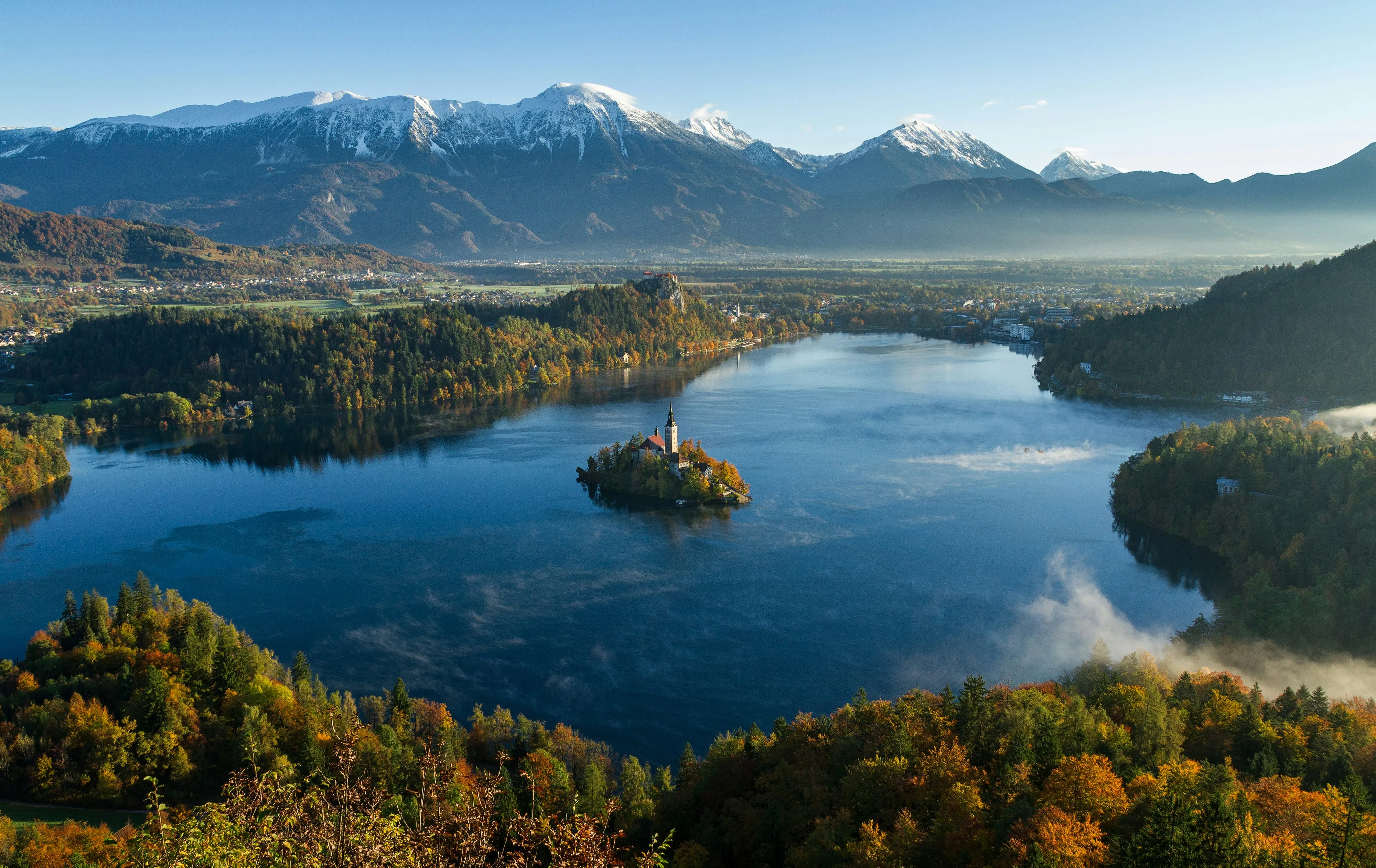 Le lac de Bled et son île à l'église, cernés de forêts d'automne sous les Alpes juliennes enneigées