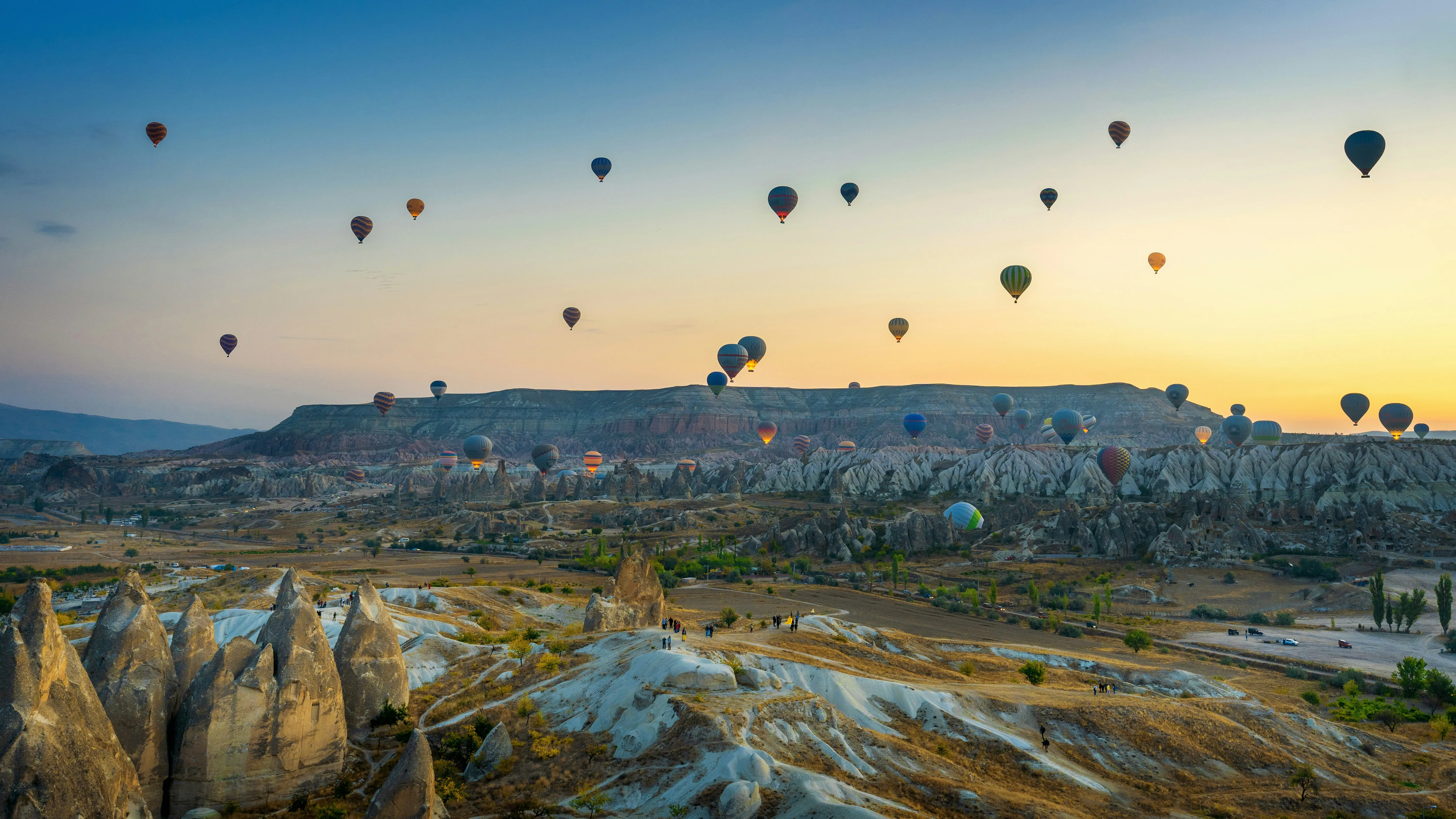 Des dizaines de montgolfières au lever du soleil sur les vallées et cheminées de fées de la Cappadoce